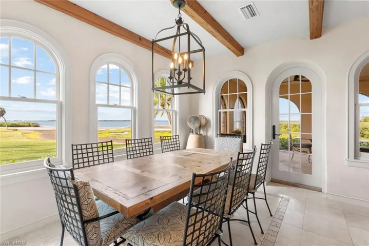 MAIN HOUSE -This dining space features exposed wooden ceiling beams and arched windows offering expansive water views