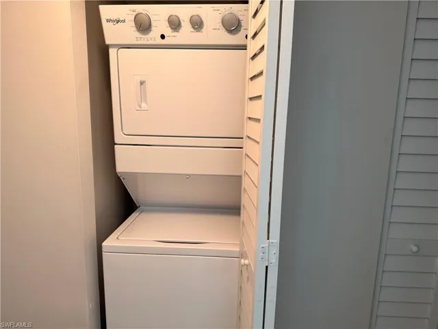 White stackable Whirlpool washer and dryer unit within a dedicated utility closet