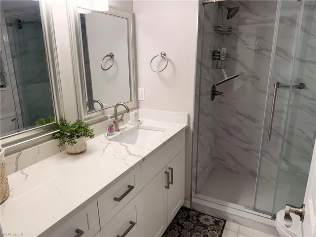 Bathroom featuring a white vanity with an integrated sink, quartz countertop, and brushed nickel hardware