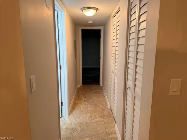 Hallway featuring patterned tile flooring, louvered bi-fold closet doors, and recessed ceiling lighting