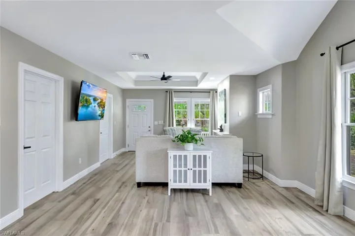 Living room featuring a tray ceiling, light wood-type flooring, and a ceiling fan