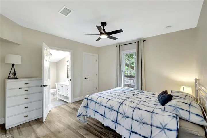 Bedroom featuring light wood finished floors, a ceiling fan, and ensuite bath