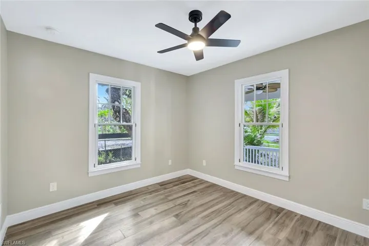 Spare room featuring light wood-style floors, healthy amount of natural light, and ceiling fan