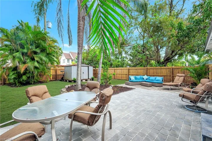 Fenced backyard featuring a storage unit, outdoor dining area, a patio area, and an outdoor hangout area