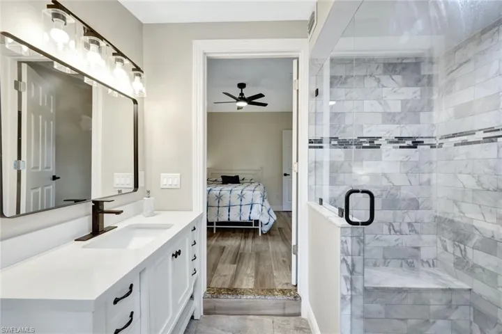 Ensuite bathroom featuring vanity, a shower stall, and a ceiling fan