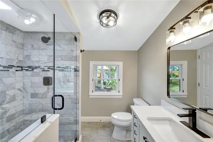 Bathroom with vanity, a shower stall, and plenty of natural light