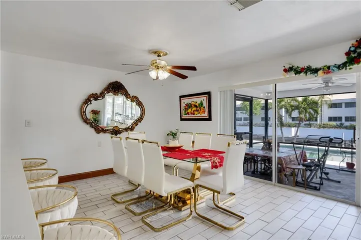 Tiled flooring extends into a space featuring a ceiling fan and a gold-framed mirror