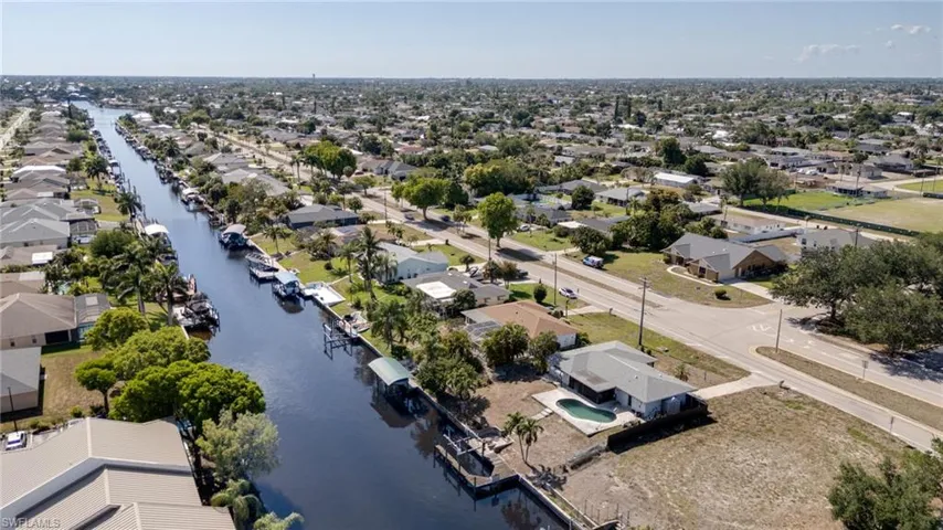 Canal-front property featuring a private boat dock and lift, mature palm trees, and an in-ground swimming pool
