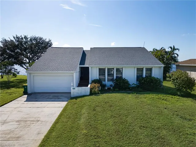 View of front of property with concrete driveway, a front yard, an attached garage, and a shingled roof