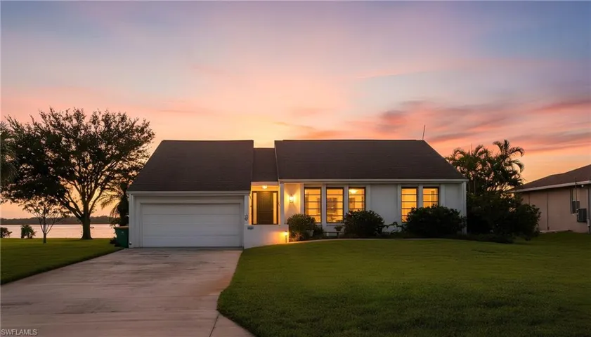 View of front of house featuring driveway, a lawn, a garage, and a shingled roof