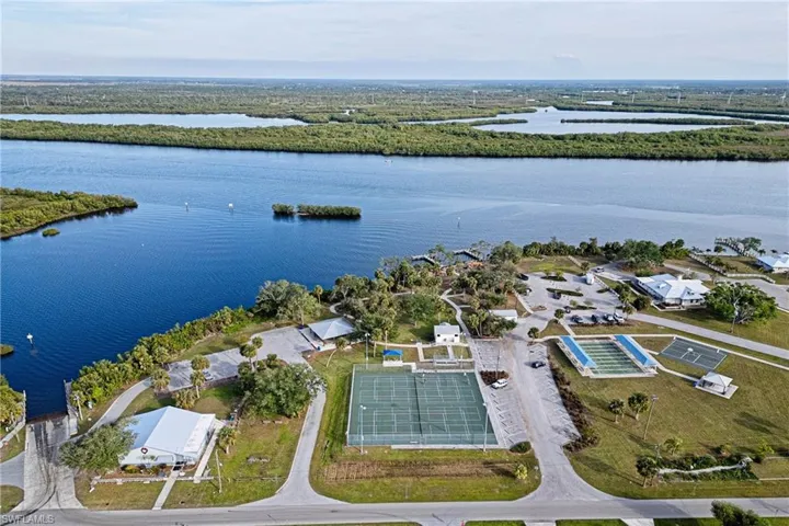Aerial view of Pickleball Courts/Tennis Courts/Shuffleboard Courtswith a large body of water and nearby suburban area