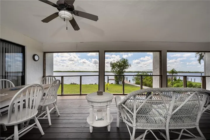 Sunroom / solarium featuring hardwood / wood-style flooring, a water view, ceiling fan, and outdoor dining area