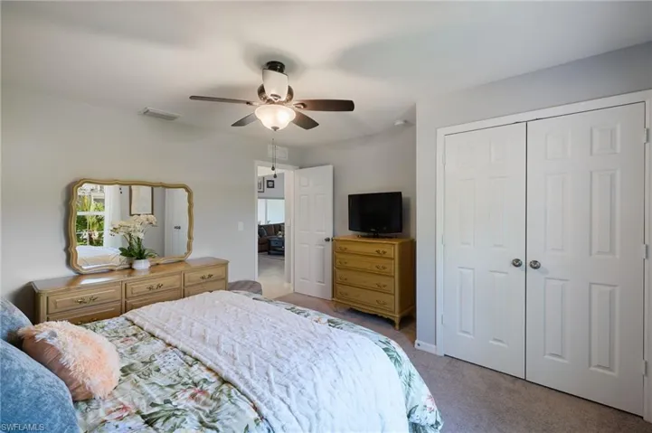 2nd bedroom with light colored carpet, closet, and ceiling fan