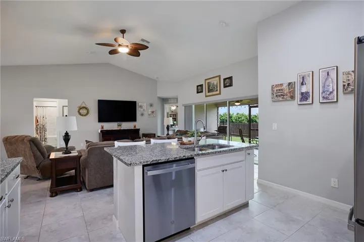 Kitchen with dishwasher, open floor plan, a ceiling fan, granite countertops, and lofted ceiling