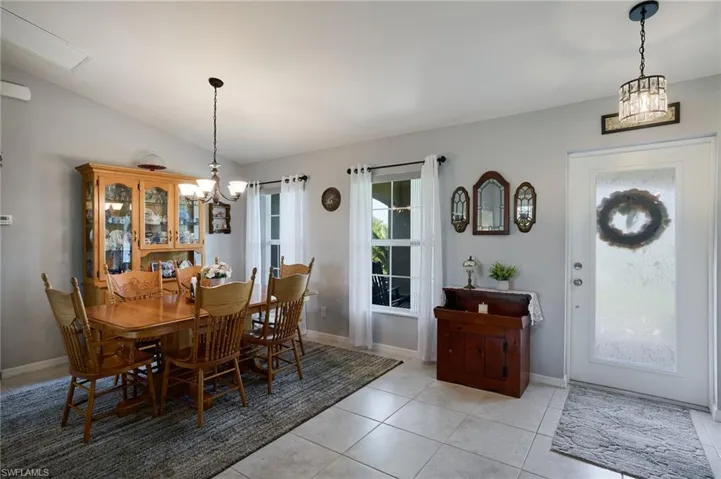 Dining room featuring a chandelier, vaulted ceiling, and light tile patterned floors
