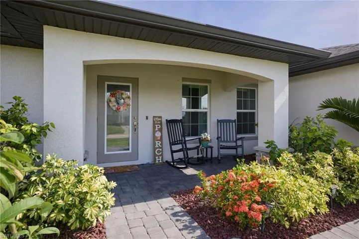 View of exterior entry with stucco siding and a porch