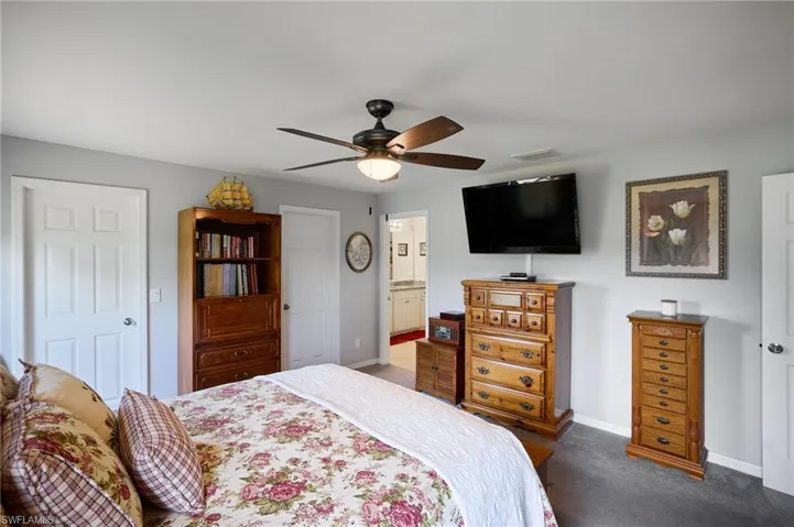 Primary bedroom featuring carpet, ceiling fan, and connected bathroom