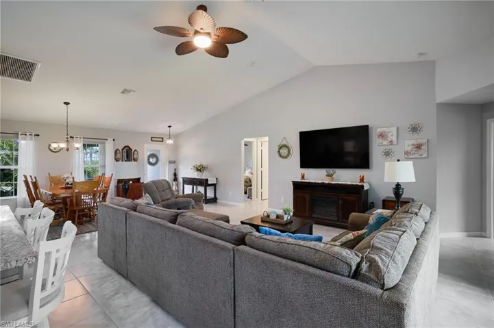 Living area featuring vaulted ceiling, light tile patterned flooring, ceiling fan, and recessed lighting