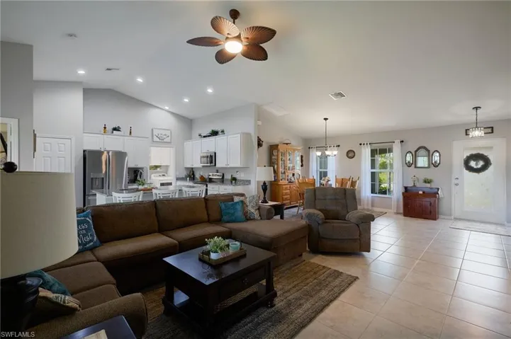 Living area featuring vaulted ceiling, light tile patterned flooring, ceiling fan, and recessed lighting