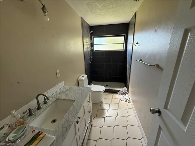 Bathroom featuring vanity, a stall shower, light tile patterned floors, and a textured ceiling