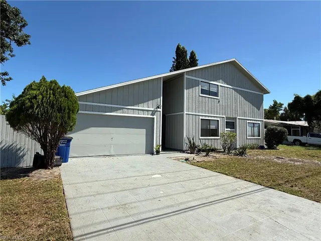 View of front of property featuring driveway, an attached garage, and a front lawn