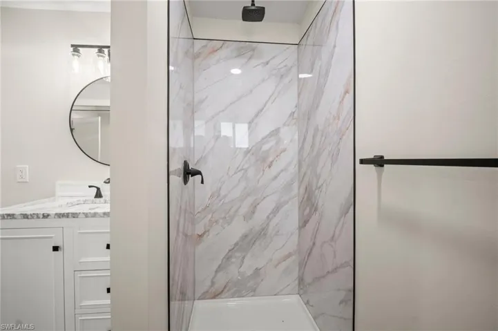 Bathroom with vanity and a marble finish shower