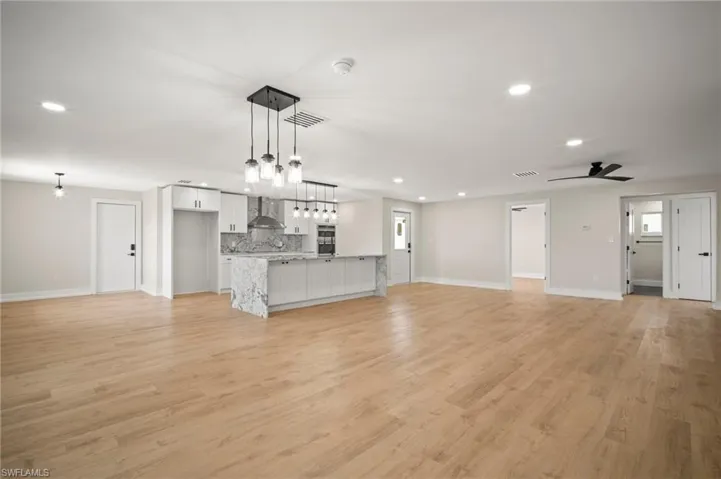 Unfurnished living room with ceiling fan, baseboards, light wood finished floors, and recessed lighting