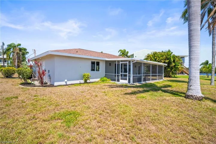 Back of property with a sunroom, stucco siding, and a yard