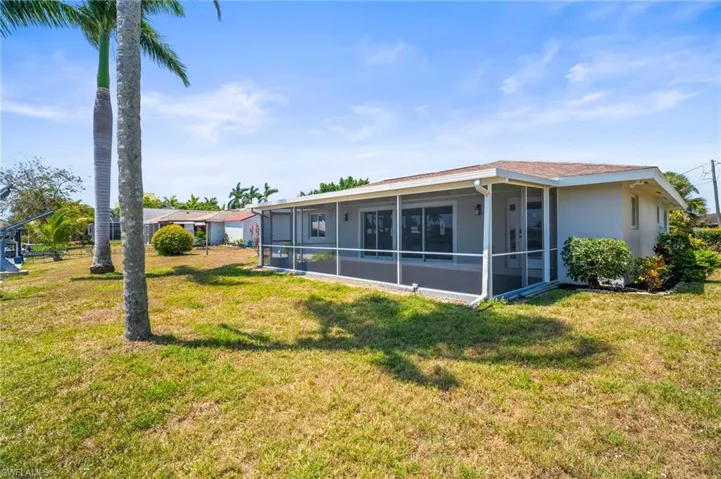 Rear view of property featuring a yard, a sunroom, and stucco siding