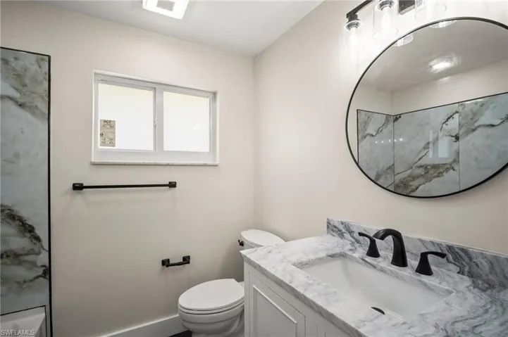 Bathroom with walk in shower, vanity, toilet, and baseboards