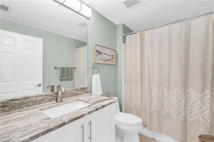 Full bathroom featuring tile patterned flooring, vanity, toilet, and shower / bath combo with shower curtain