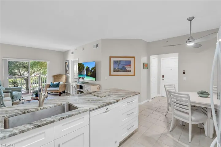 Kitchen featuring light stone countertops, ceiling fan, sink, dishwasher, and white cabinets
