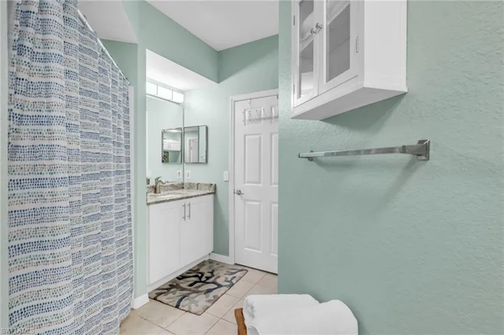 Bathroom with curtained shower, tile patterned flooring, and vanity