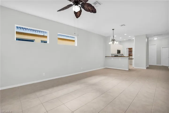 Unfurnished living room featuring ceiling fan with notable chandelier and light tile patterned floors