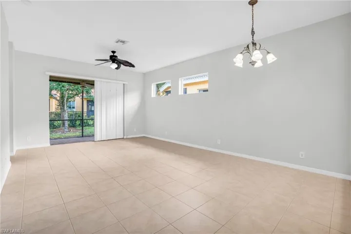 Tiled great room with ceiling fan with notable chandelier