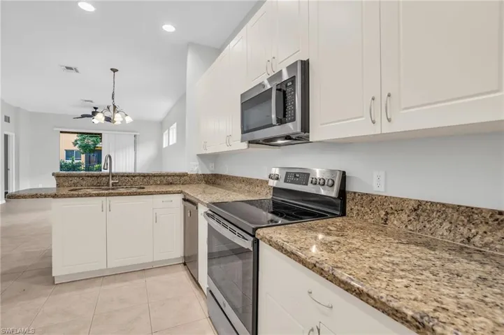 Kitchen with white cabinetry, light tile patterned floors, light stone counters, appliances with stainless steel finishes, and sink