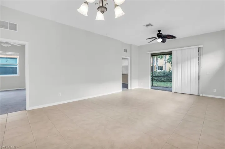 Spare room featuring light tile patterned flooring and ceiling fan with notable chandelier
