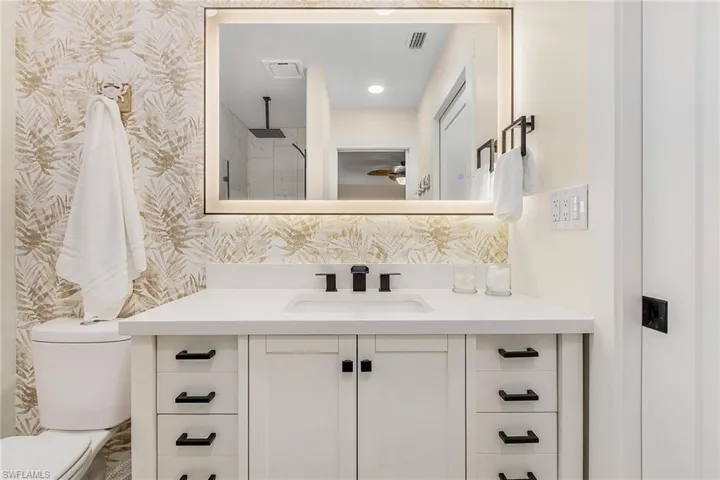Bathroom with vanity with extensive cabinet space and toilet
