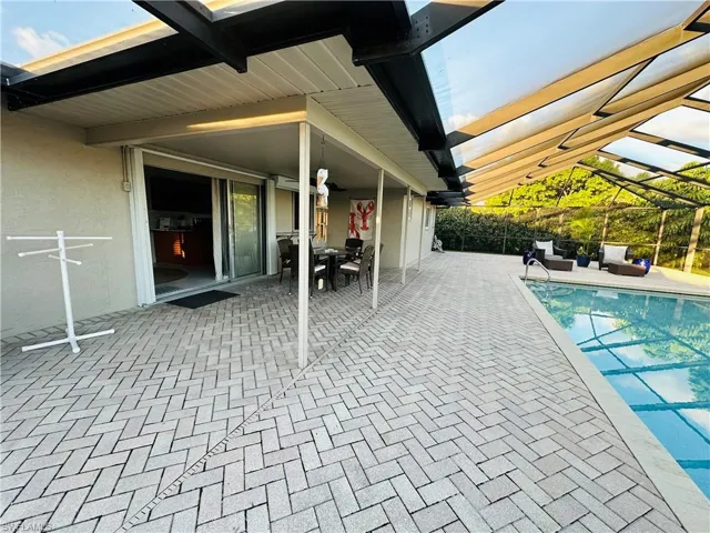 View of swimming pool with glass enclosure and a patio