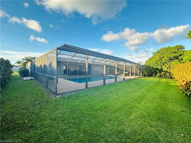 Back of house featuring glass enclosure and a yard