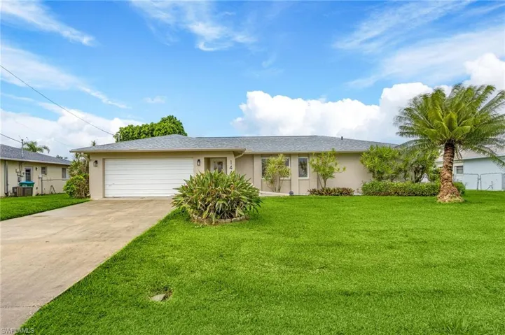 Single story home with a garage and a front lawn