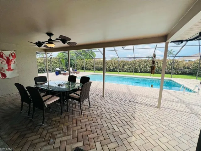 View of swimming pool featuring glass enclosure, a patio area, and ceiling fan