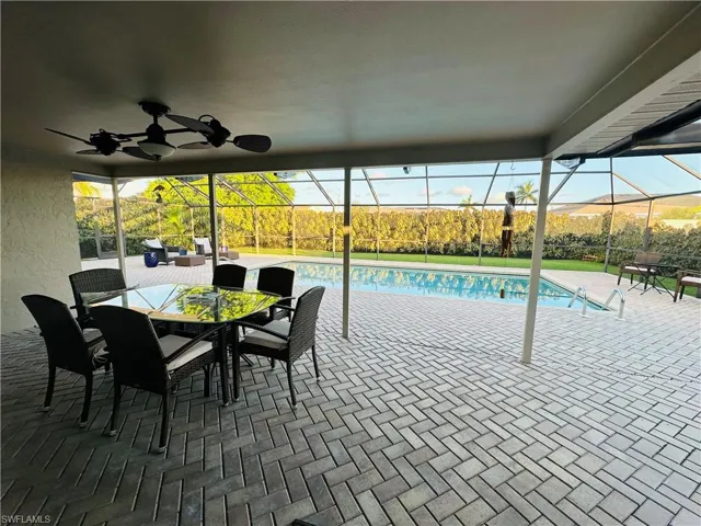 View of swimming pool with ceiling fan, a lanai, and a patio area