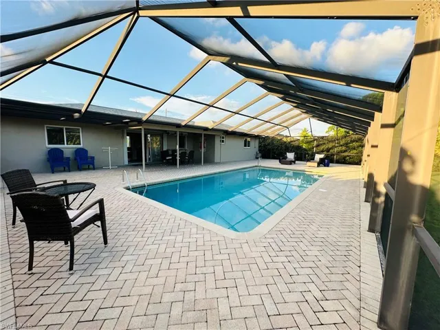 View of pool featuring a patio area and glass enclosure