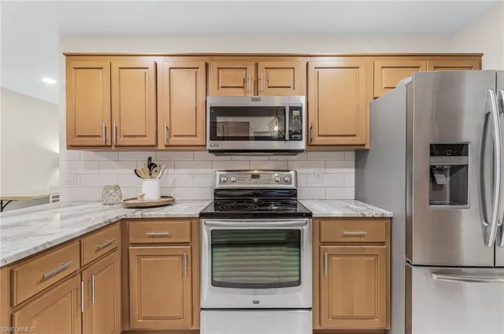 Kitchen featuring stainless steel appliances, light stone counters, and tasteful backsplash