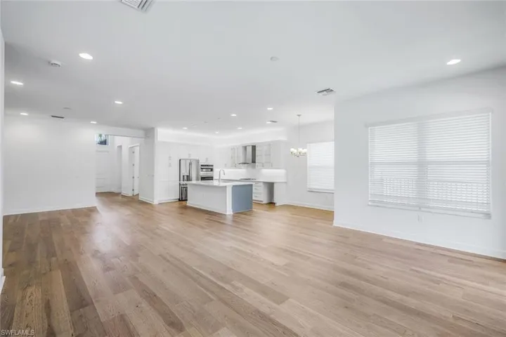 Unfurnished living room with sink, an inviting chandelier, and light wood-type flooring
