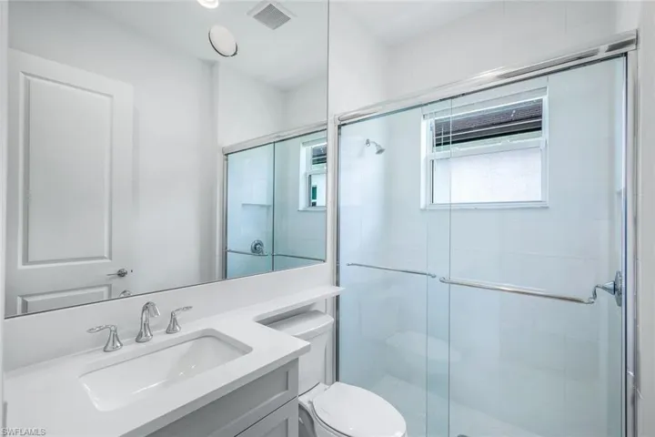 Bathroom featuring a shower with shower door, toilet, and vanity