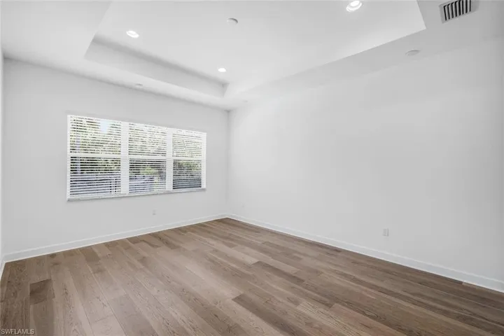 Unfurnished room with a tray ceiling and hardwood / wood-style floors