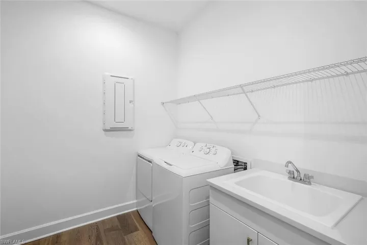 Washroom featuring hookup for a washing machine, dark wood-type flooring, washing machine and dryer, sink, and cabinets