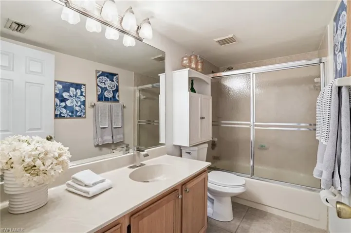 Bathroom featuring vanity, light tile patterned floors, and shower / bath combination with glass door